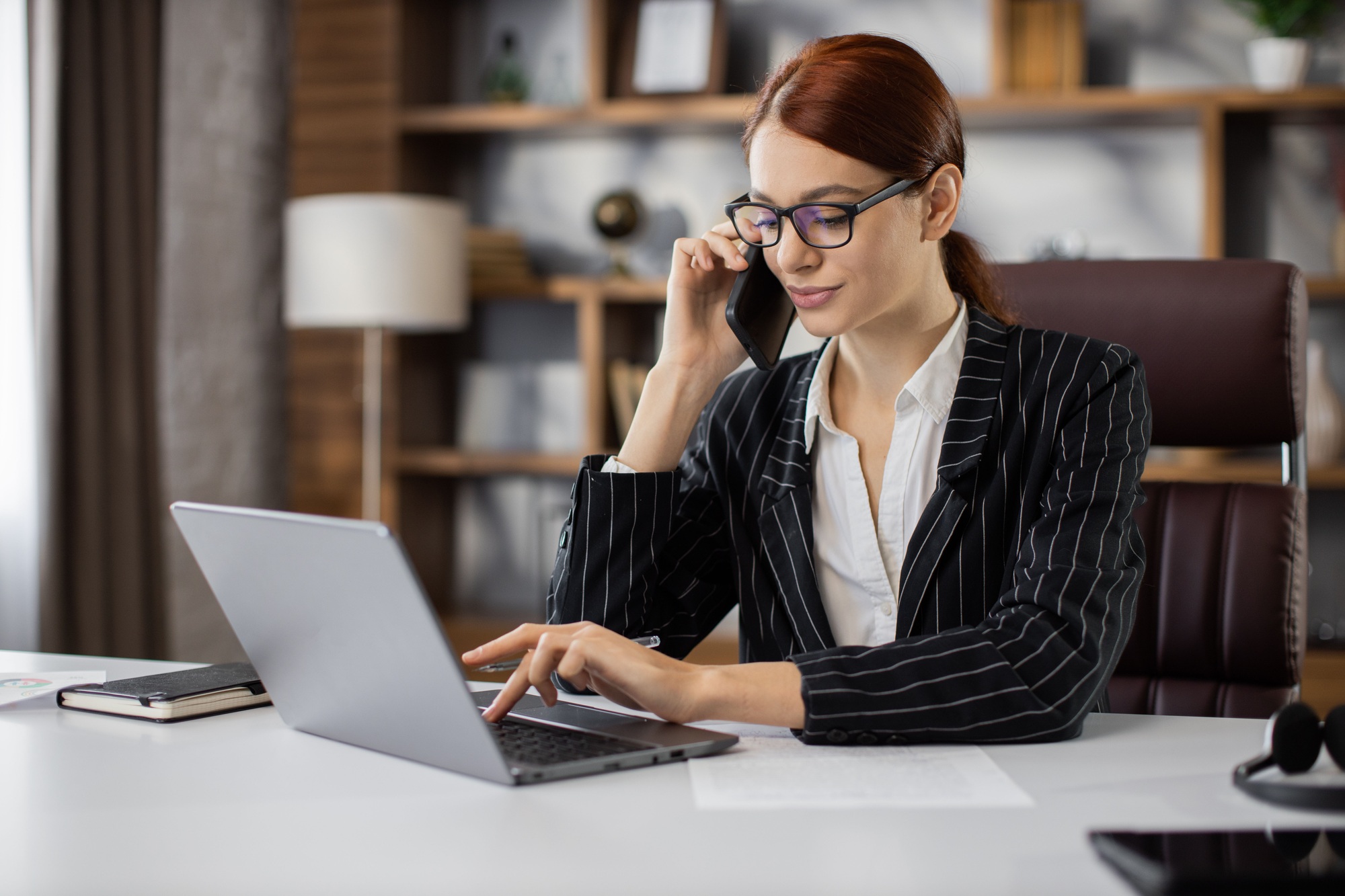 Confident young pretty woman in glasses calling to her business partners